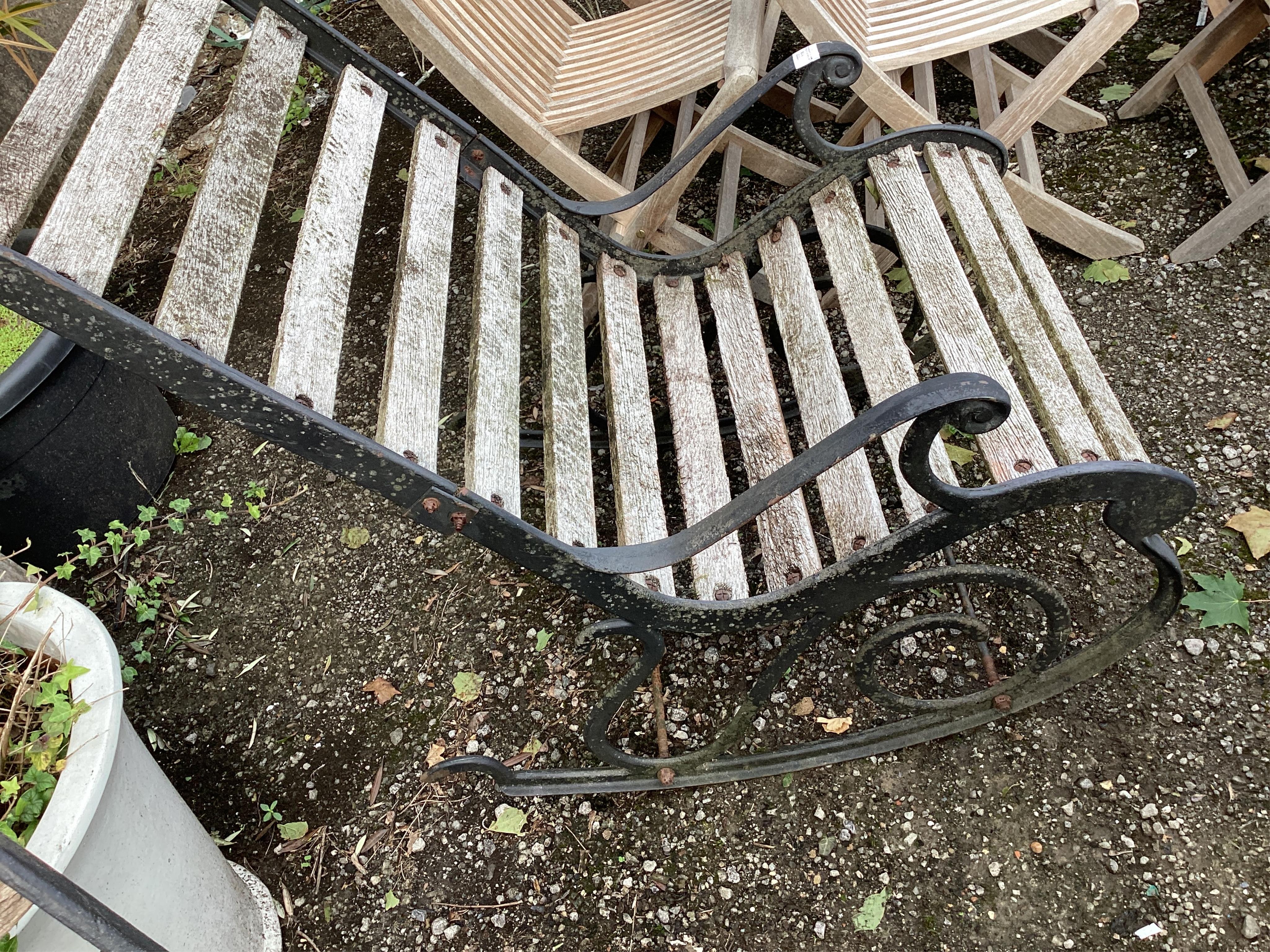 A pair of slatted cast metal garden rocking chairs